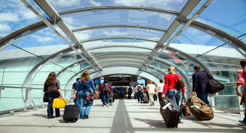 passengers with luggage walking through glass tunnel