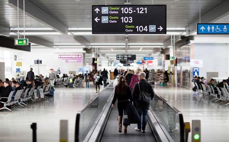 passenger walking with 100 gates signage over head